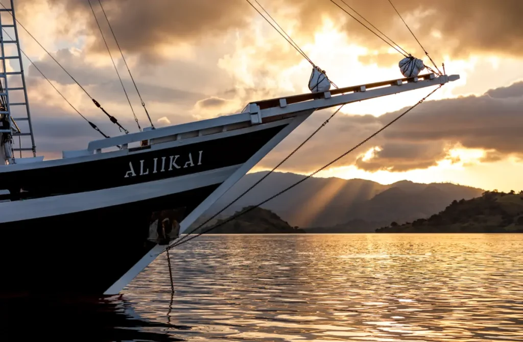 Bow of Aliikai phinisi yacht at golden hour in Komodo